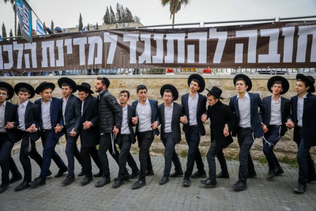 בחורי ישיבה על רקע שלטי ההפגנה היום מול ביתו של דרעי.