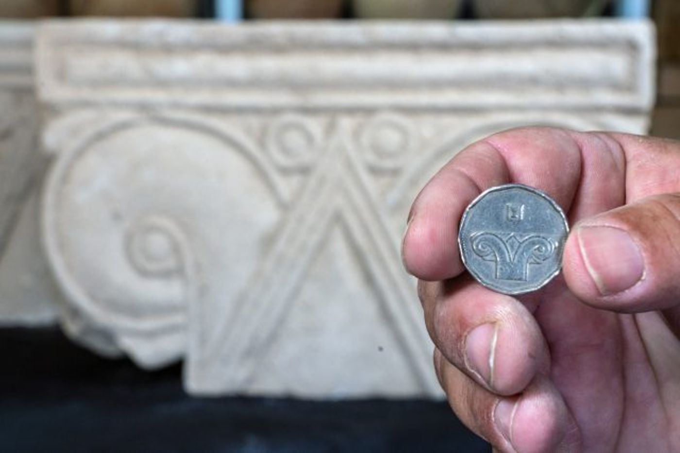 מטבע 5 שקלים על רקע הכותרת שנתגלתה.