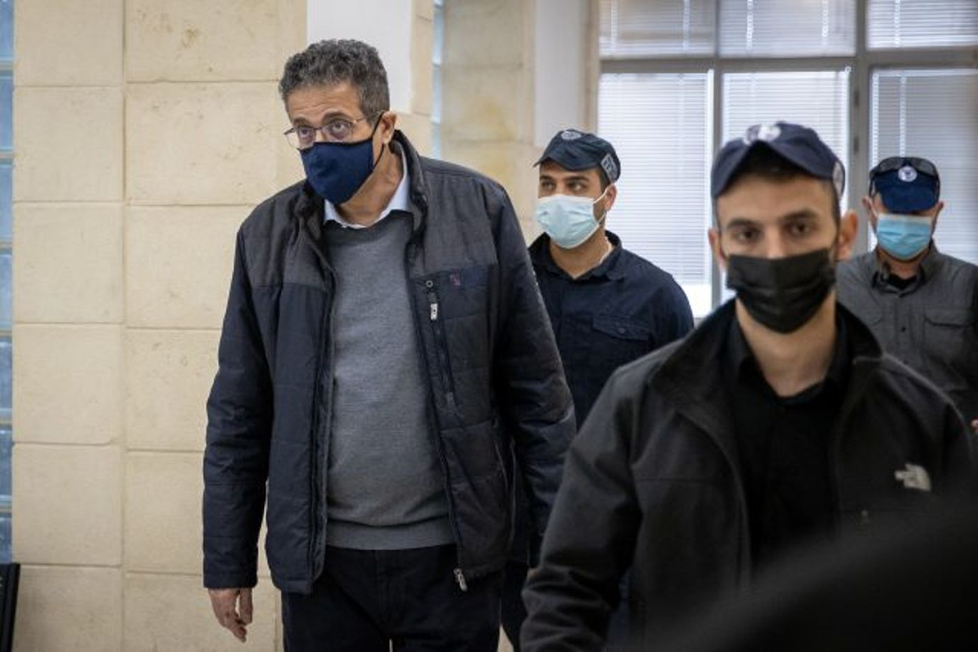 עד התביעה המרכזי בתיק 4000, אילן ישועה, עם מאבטחי המשטרה בבית המשפט המחוזי בירושלים (יונתן זינדל/פלאש 90)