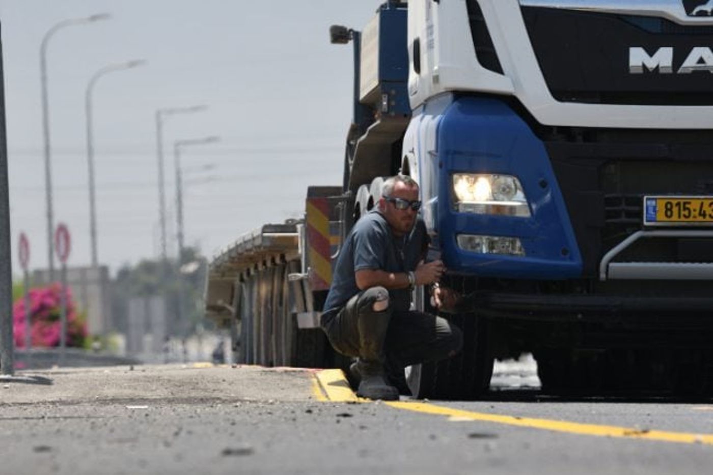 נהג מסתתר מאחורי משאית במהלך אזעקה בעקבות שיגור רקטות מעזה