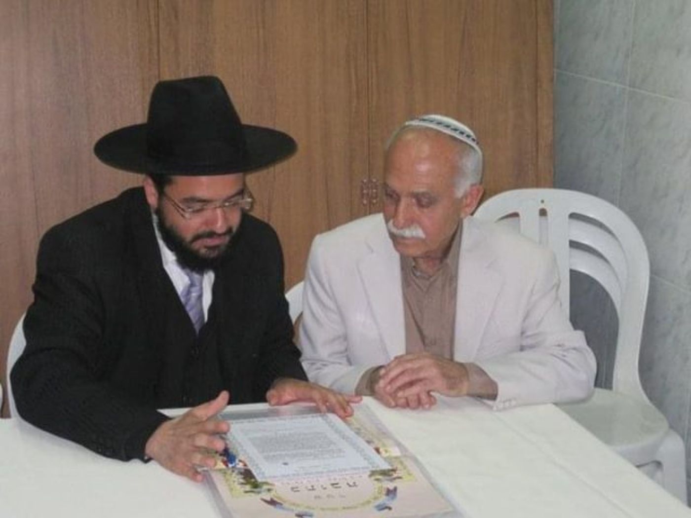 סבי יושב לחתום על הכתובה עם הרב שחיתן אותו ואת סבתי