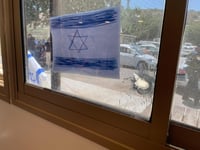 חור של כדור בחלון ודגל ישראל