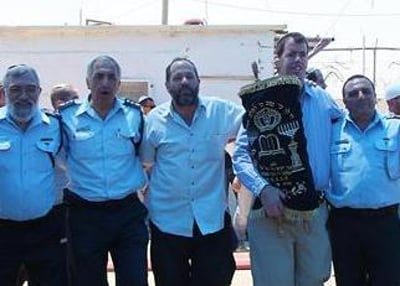 שוטרים ומתיישבים רוקדים יחד בחברון עם ספר התורה